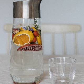 KINTO LUCE Water Carafe with stainless steel top filled with infused fruit and glass tumbler beside it