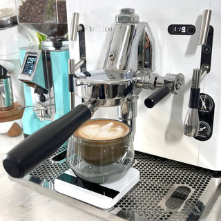 KRUVE IMAGINE Glasses (2-Pack) holding latte with visible foam, hand-blown borosilicate glass on espresso machine tray