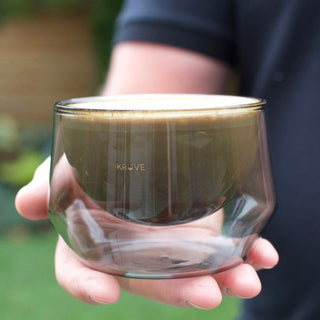 KRUVE IMAGINE Glasses (2-Pack) held, showing clear hand-blown borosilicate glass with coffee inside